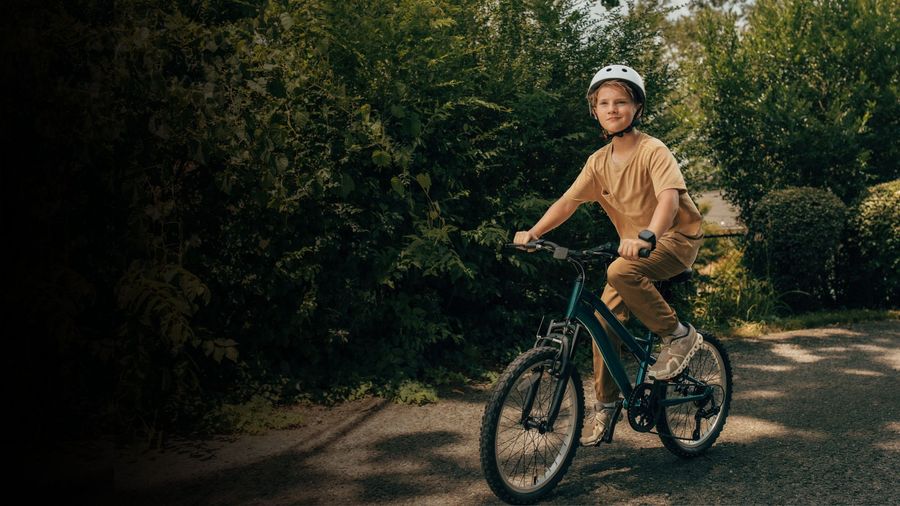 A kid riding a bike on a leafy path
