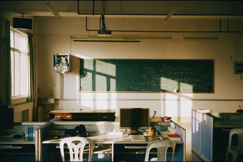 An empty classroom with a chalkboard in afternoon sun